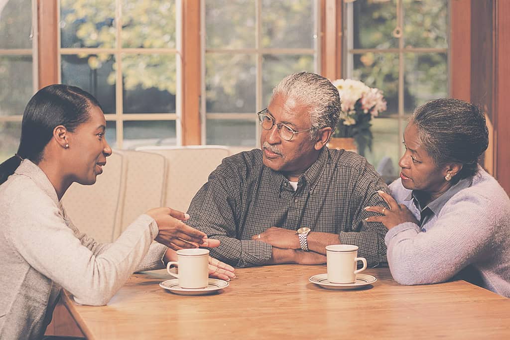Family members engaging in a heartfelt conversation at a table with coffee cups, focusing on elderly CARE.