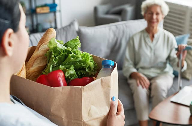 A TRUE CALLING TO SERVE OTHERS: OUR DIVERSE HOMECARE AGENCY 1 AMERICARE CAREGIVER BRINGING GROCERIES TO CLIENT AFTER RUNNING ERRANDS