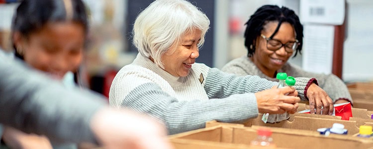 THE POWER OF CONNECTION 2 SENIOR WOMAN VOLUNTEERING AT A LOCAL FOOD BANK