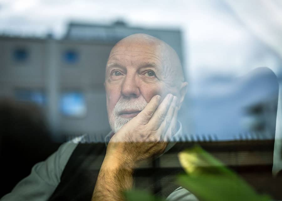 Portrait of thoughtful senior man looking through window