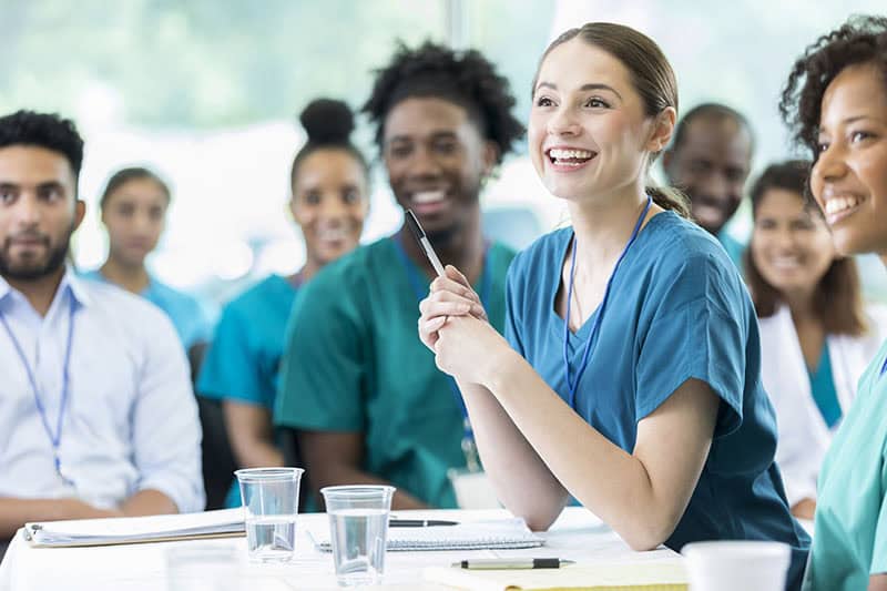 Cheerful Hispanic female nursing students smiles as she listens to a professor's lecture