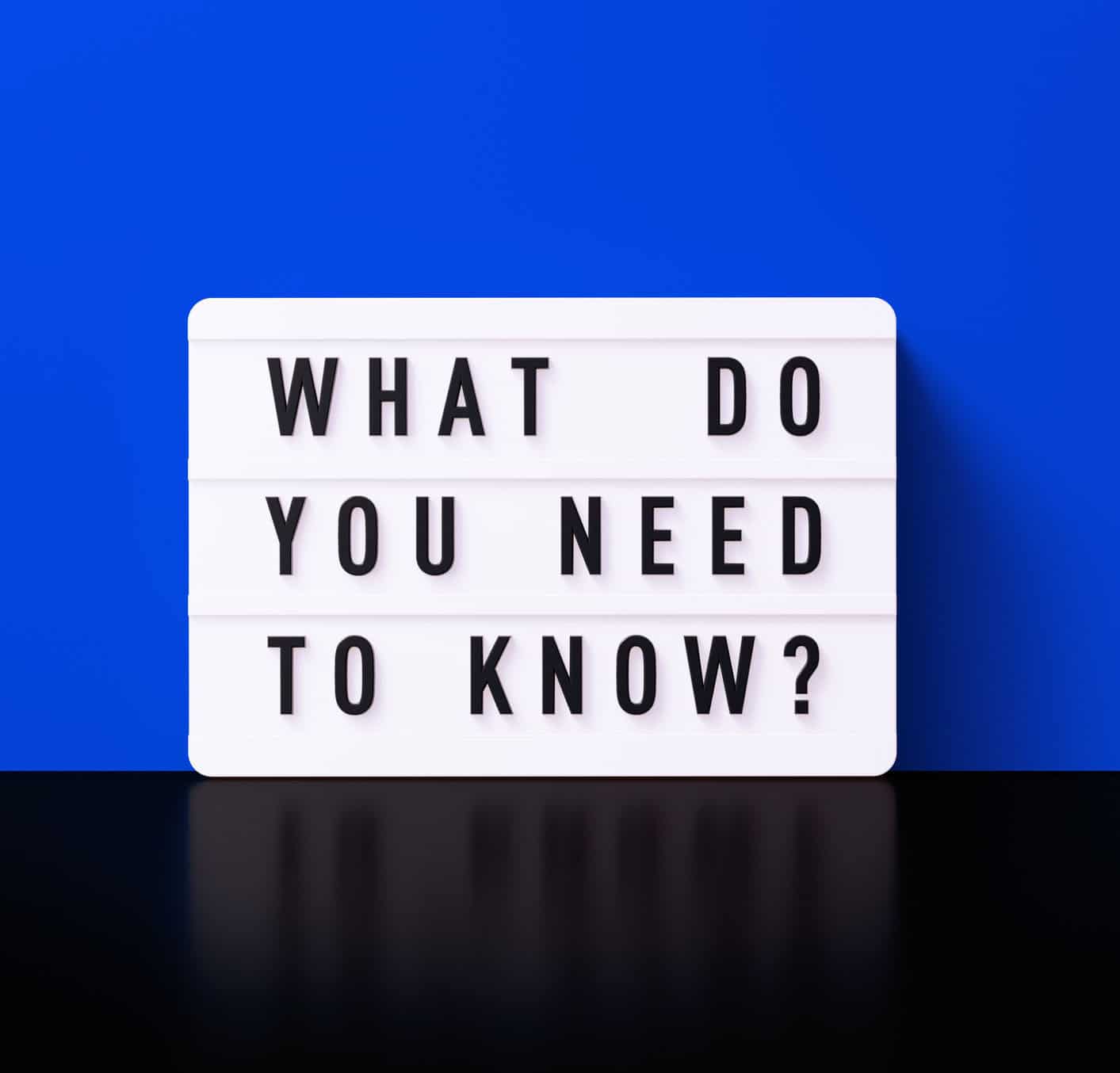What do you need to know written white lightbox before blue wall. Horizontal composition with copy space.
